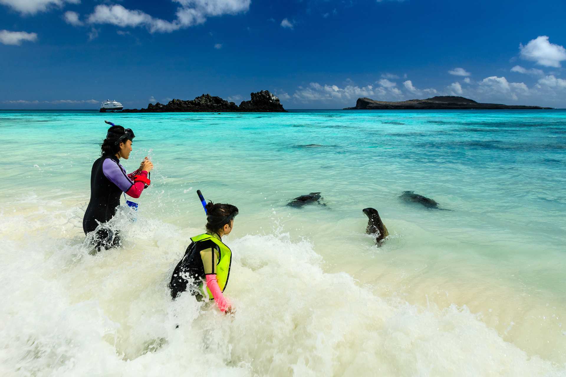 Mother and child watch sea lions on shores of Gardner Bay, Española Island, Galápagos