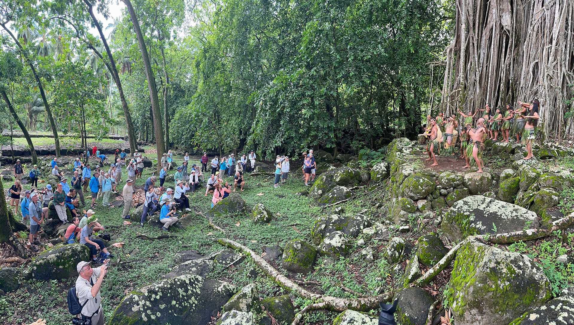 numerous guests watching dancers perform on top of a large rock