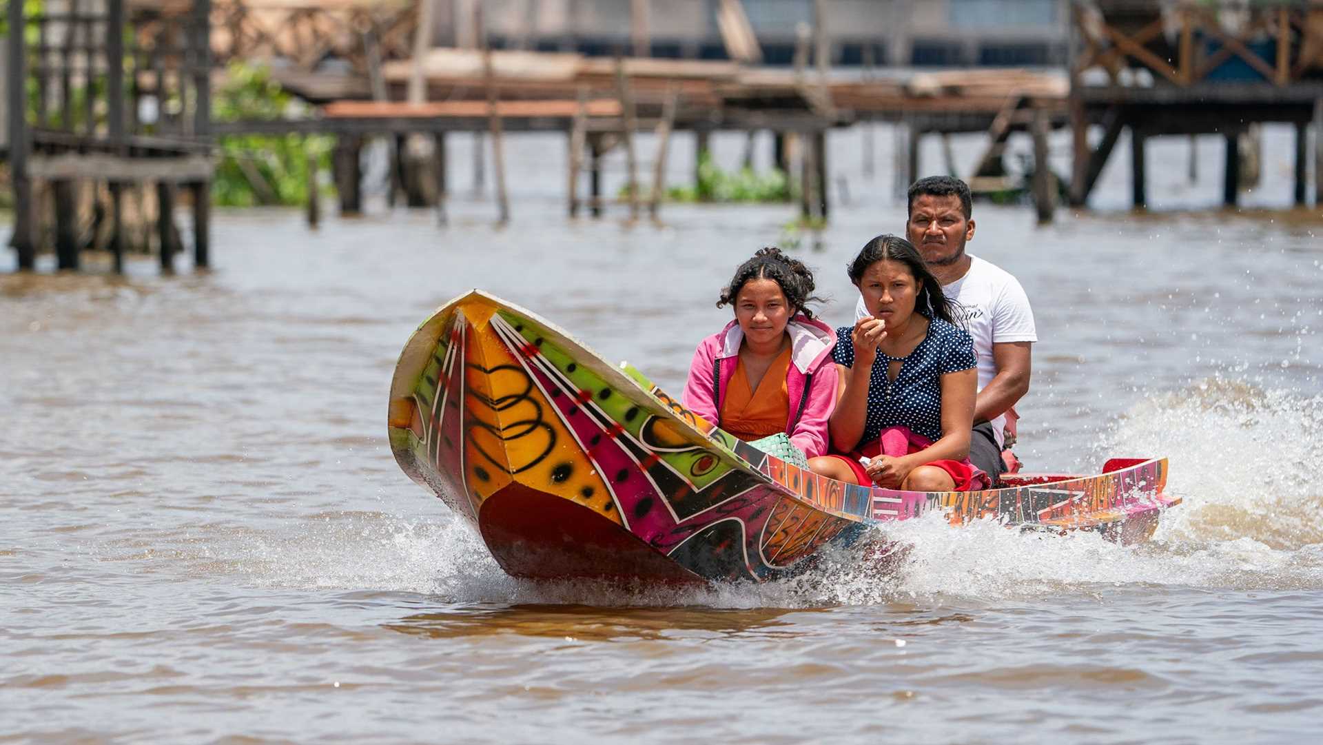 three people ride in a colorful boat